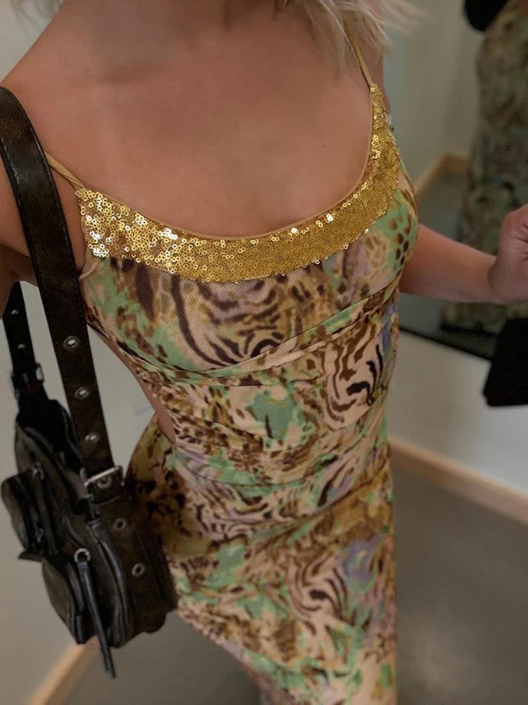 Person wearing a patterned dress with a gold sequin top, holding a black bag.