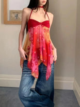 Woman wearing a colorful top with floral patterns and blue jeans indoors.