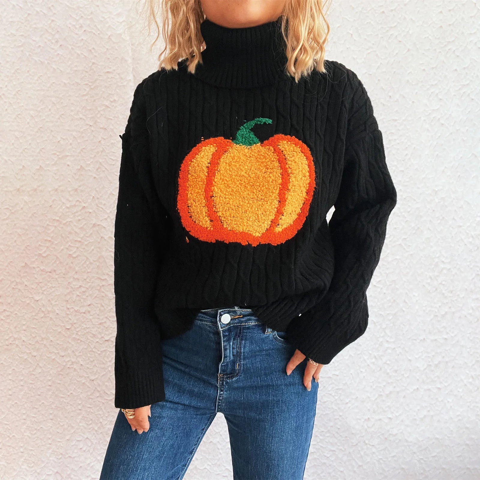 Person wearing a black sweater with a pumpkin design