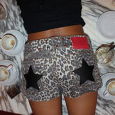 Person wearing leopard print shorts with star designs on a marble table with coffee cups.
