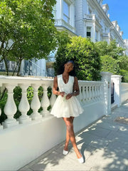 Woman in a white dress standing in front of a classical building with greenery.