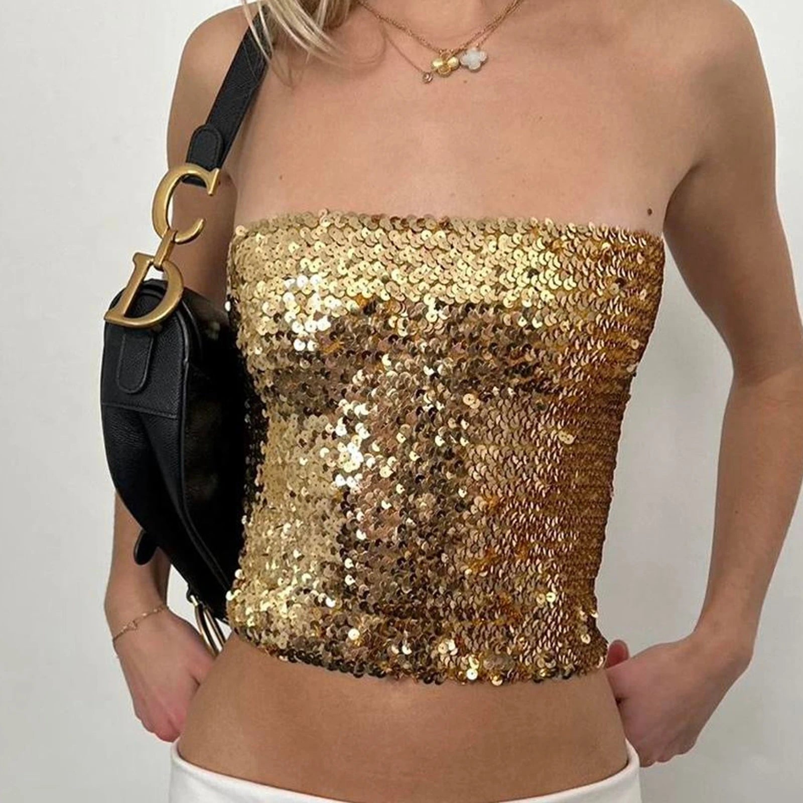 Gold sequin strapless top worn by a person with a black handbag