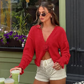 Woman wearing a red cardigan and white shorts, holding drinks, with a floral background.