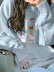 Light gray sweater with colorful graphics and text worn by a person.