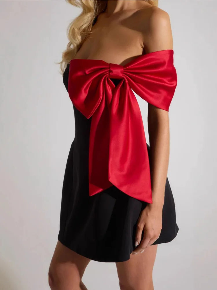 Black dress with a large red bow on a plain background