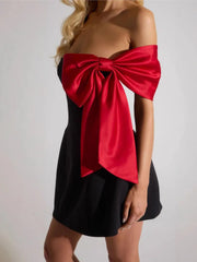 Black dress with a large red bow on a plain background
