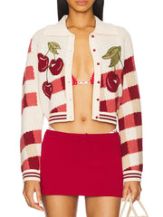 Woman wearing a red and white checkered cardigan with cherry designs over a matching skirt