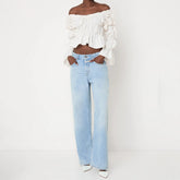 Person wearing a white off-shoulder top and light blue jeans