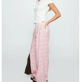 Person wearing a white top and pink striped pants on a light gray background