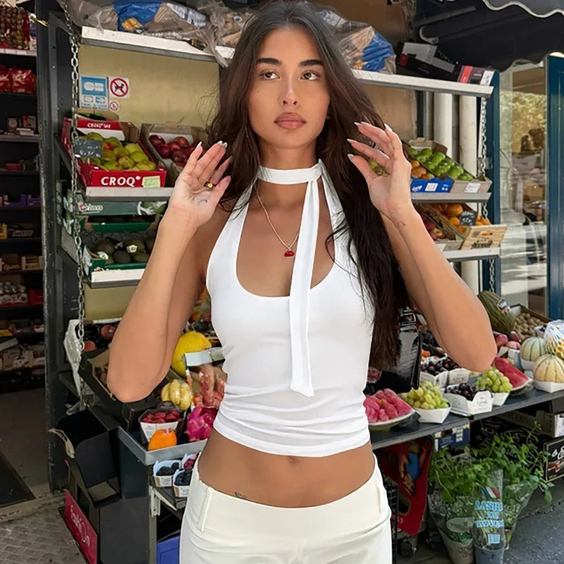 Woman in a white outfit standing in a grocery store with produce in the background