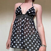 Black dress with white polka dots worn by a person against a plain background
