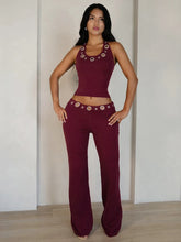 Woman wearing a burgundy outfit with decorative elements against a plain background