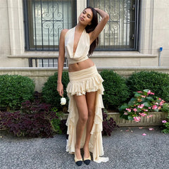 Woman in a beige dress standing in front of a building with decorative elements.