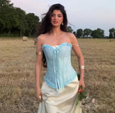 Woman in a light blue and white dress standing in a field