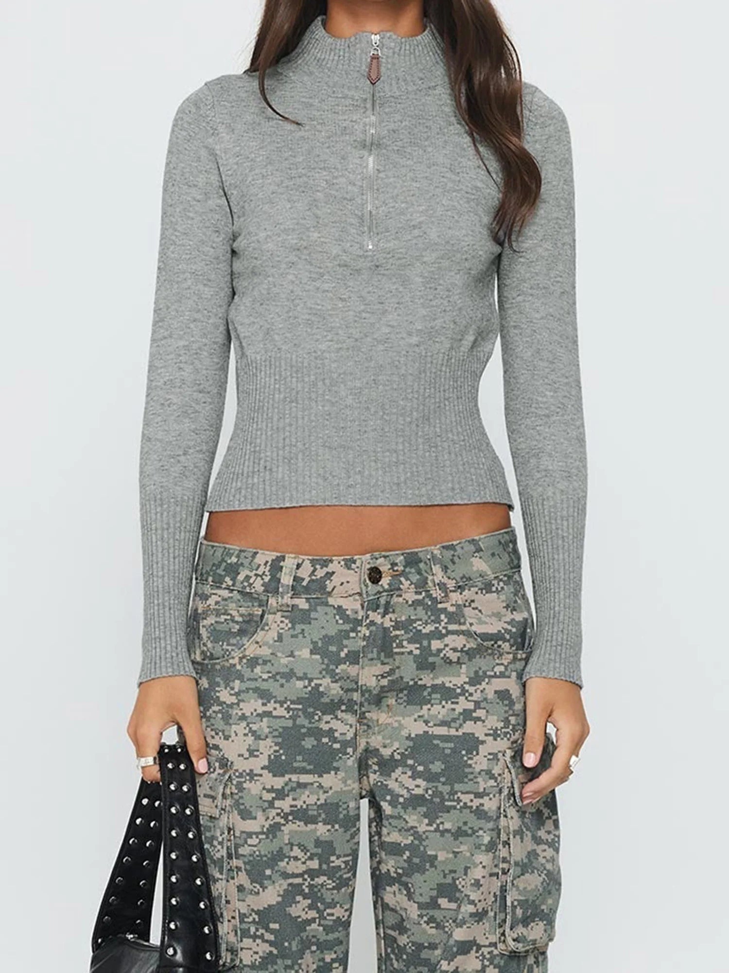 Person wearing a gray long-sleeve top and camouflage pants on a white background
