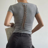 Person wearing a gray t-shirt with cut-out design on the back, standing against a plain background.