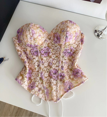 Floral-patterned sun hat on a white surface with sunglasses and a black bag in the background.