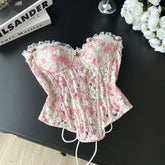 Floral-patterned corset on a dark surface with books and flowers in the background