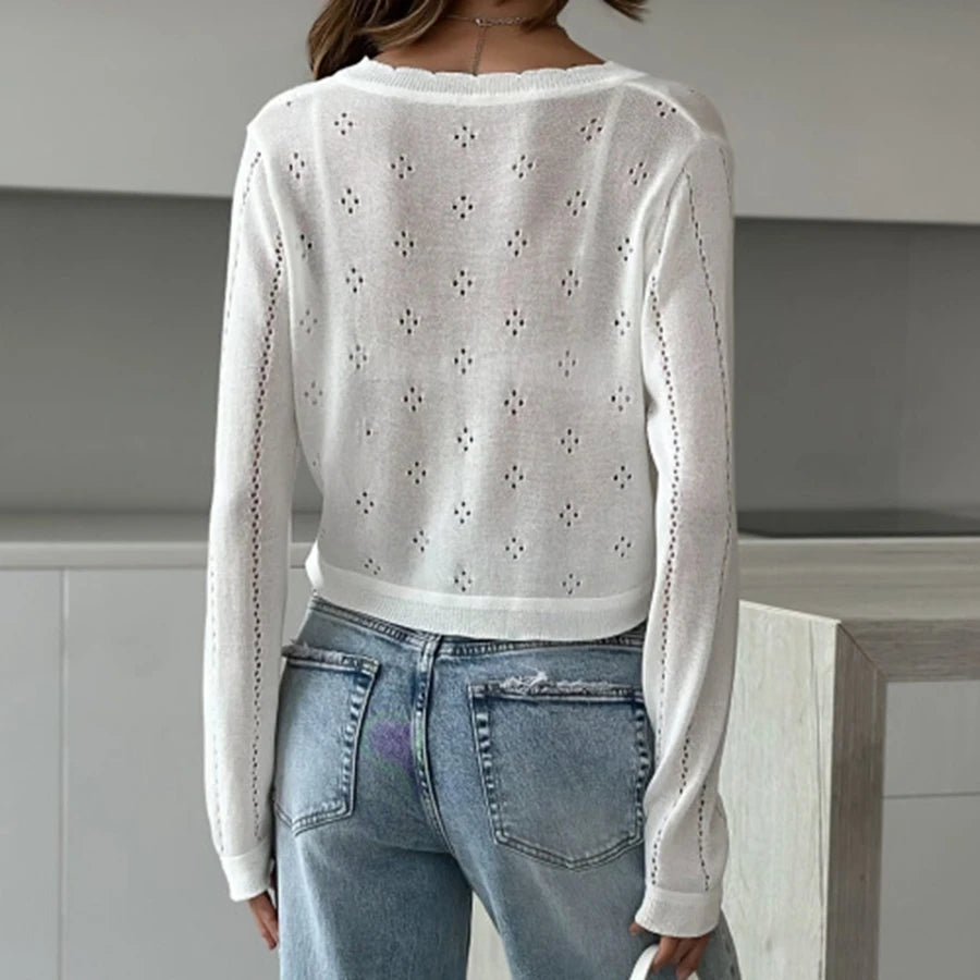 Person wearing a white lace-up top and blue jeans in an indoor setting