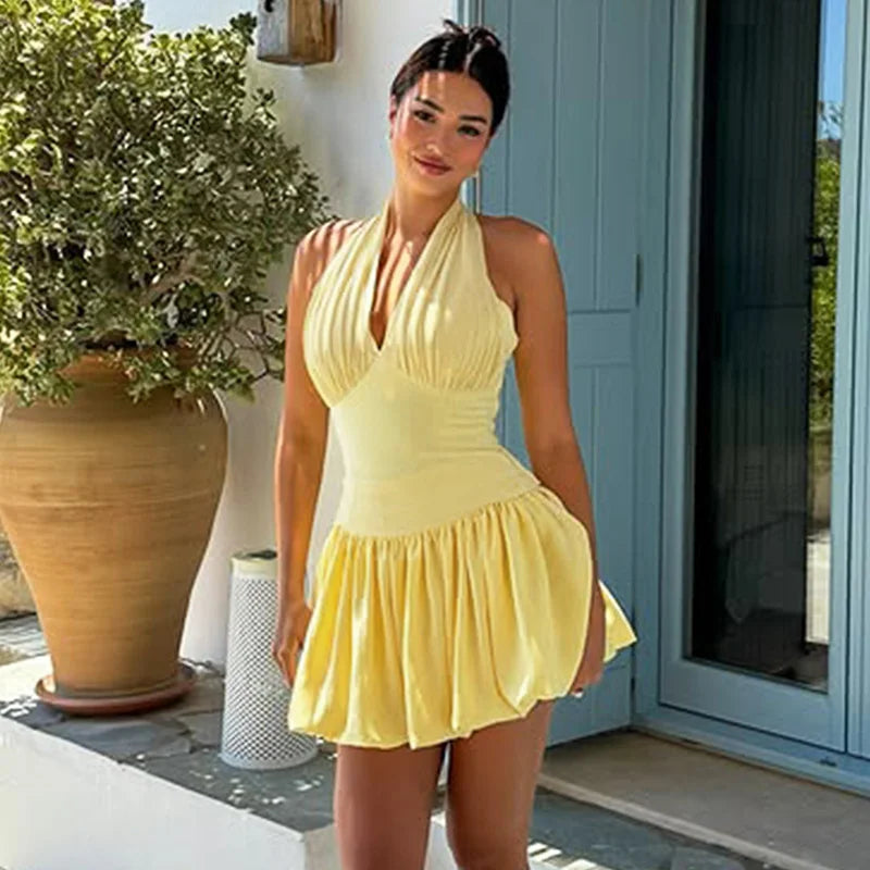 Woman in a yellow dress standing outdoors near a building entrance.