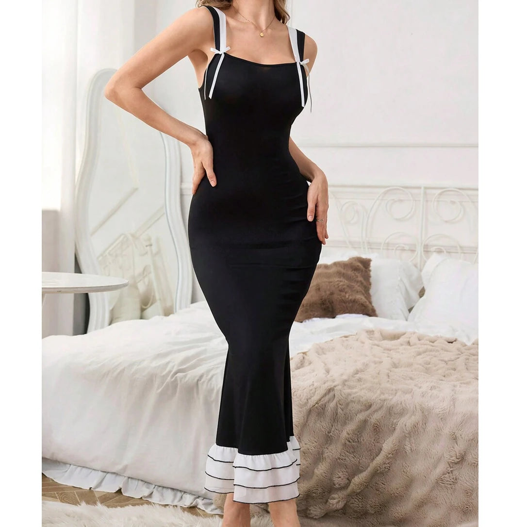 Woman wearing a black dress with white trim in a bedroom setting