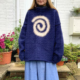 Person wearing a blue sweater with a white spiral design outdoors.
