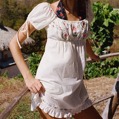 Woman wearing a white dress with floral patterns in an outdoor setting
