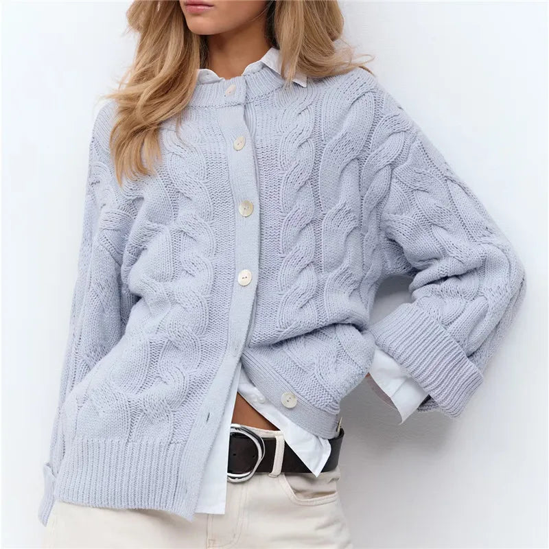 Person wearing a light blue cable knit cardigan over a white shirt on a white background