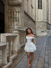 Woman in a white dress standing in front of a stone building with statues.