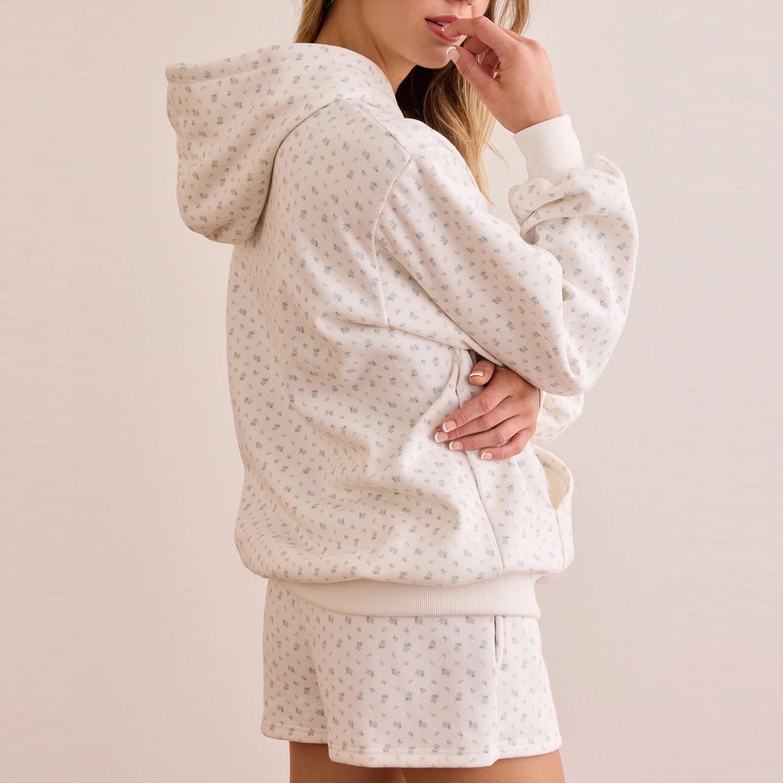 Person wearing a matching hoodie and shorts set with a subtle pattern on a plain background