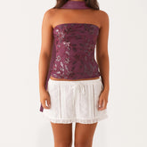 Woman wearing a purple floral top and white lace skirt