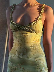 Woman wearing a gold dress with intricate detailing on a plain background
