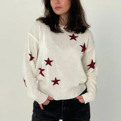 Person wearing a white sweater with red star patterns