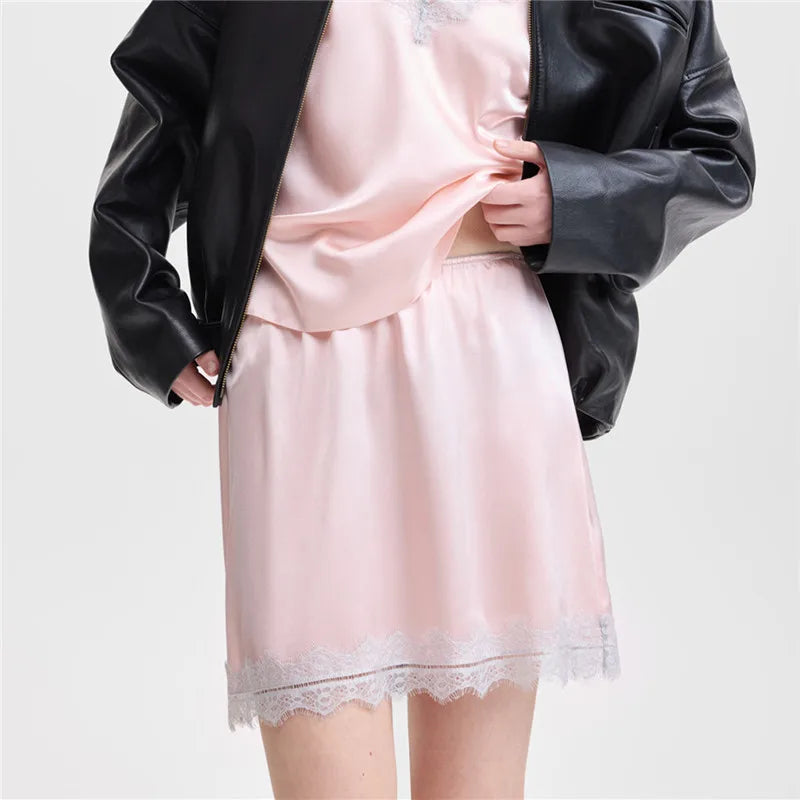 Person wearing a pink satin nightgown with lace hem and a black leather jacket on a white background