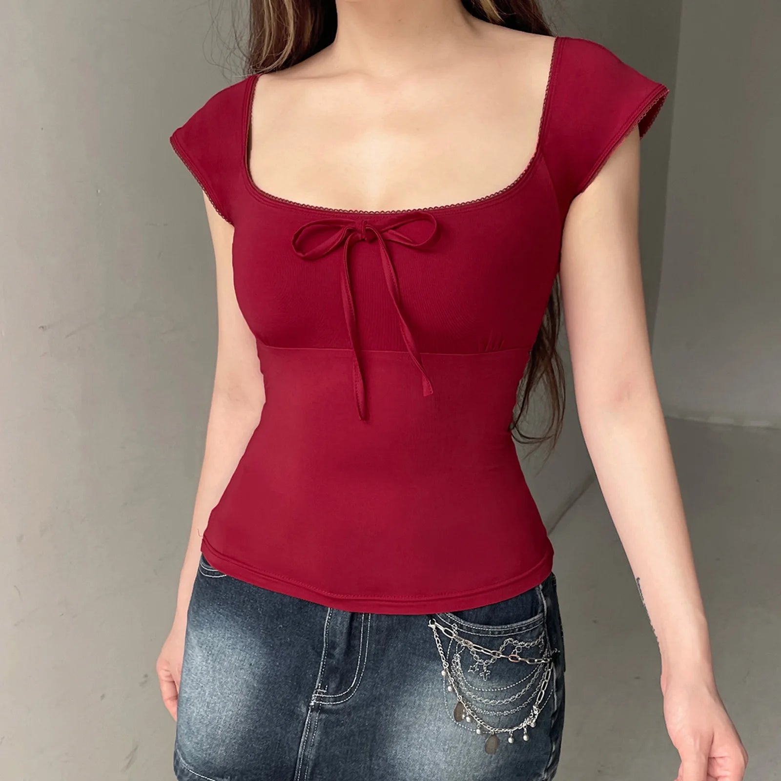 Red top with a bow detail worn by a person against a neutral background