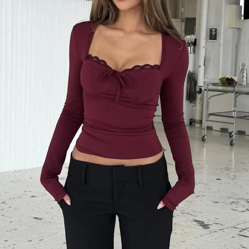 Woman wearing a burgundy long-sleeve top with lace detailing in an indoor setting.