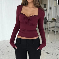 Woman wearing a burgundy long-sleeve top with lace detailing in an indoor setting.
