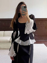 Person wearing a black and white outfit with ruffled details in an indoor setting.