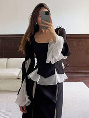 Person wearing a black and white outfit with ruffled details in an indoor setting.