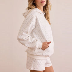 Woman wearing a white patterned hoodie and shorts set on a beige background