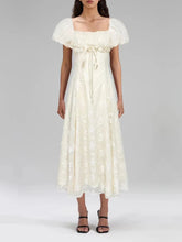 Woman wearing a white dress with puffed sleeves on a plain background