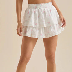 White lace skirt with floral patterns worn by a person on a beige background