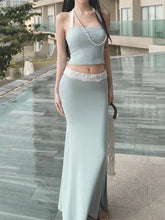 Woman in a light blue dress standing by a poolside.