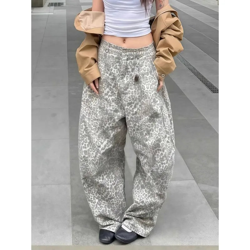 Person wearing leopard print pants and a beige jacket on a gray floor.