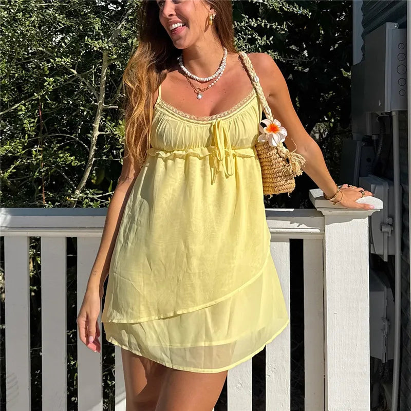 Woman in a yellow dress standing on a white railing with greenery in the background