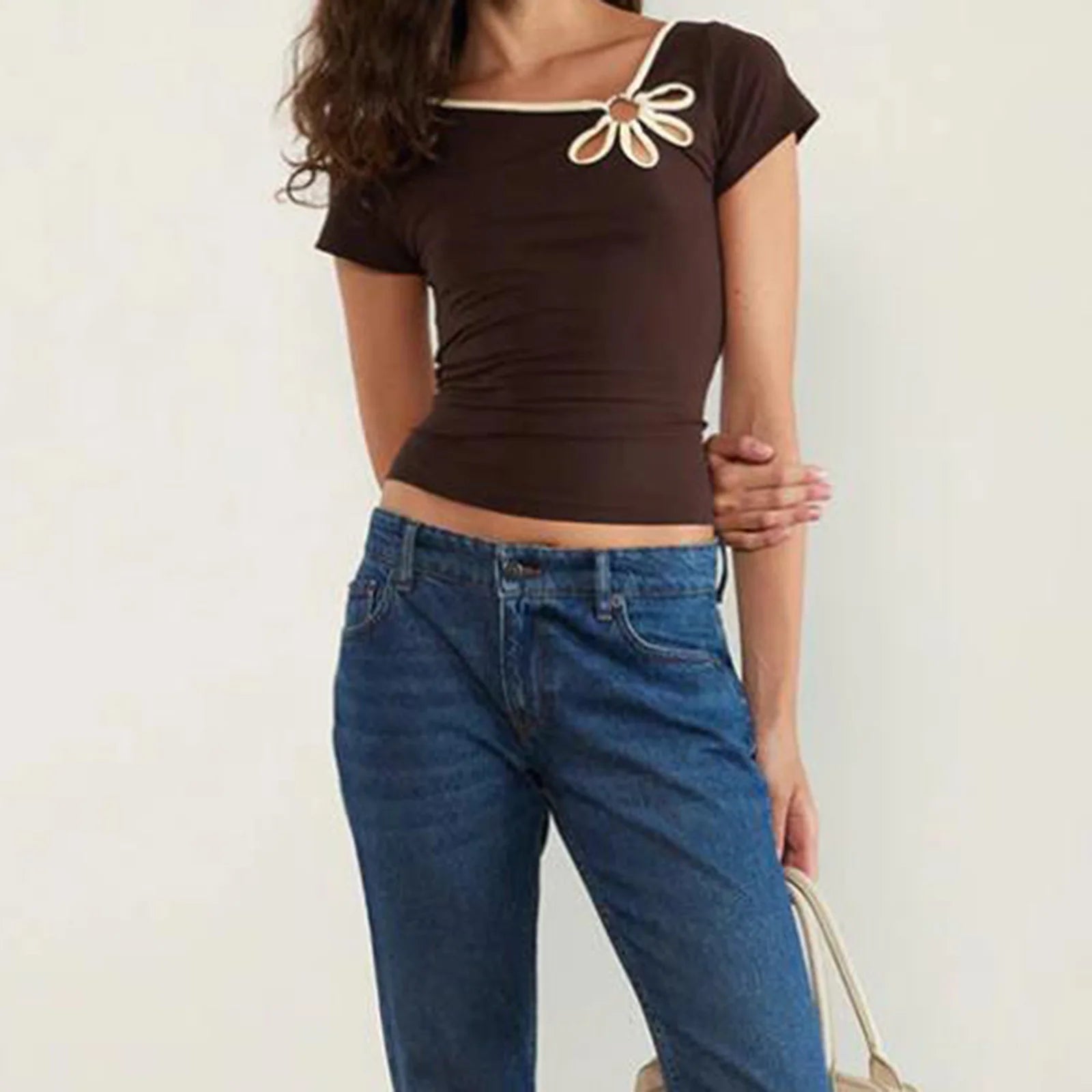Person wearing a brown crop top with floral details and blue jeans