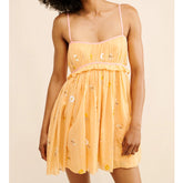 Woman wearing a yellow dress with floral patterns on a beige background