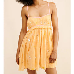 Woman wearing a yellow dress with floral patterns on a beige background