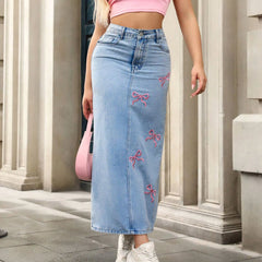 Person wearing a light blue denim skirt with pink bows, standing in front of classical architecture.