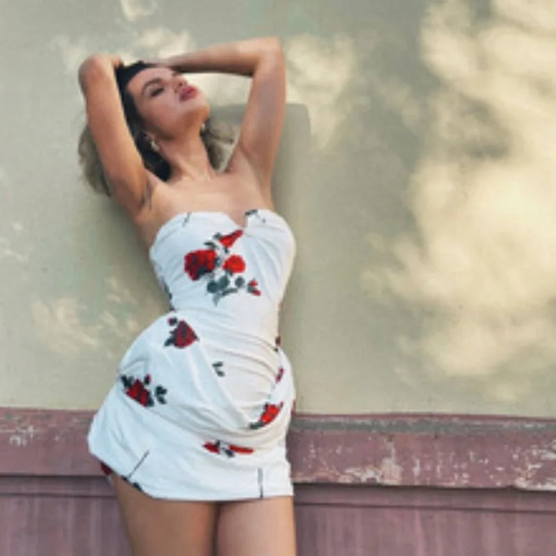 Woman wearing a white dress with red floral patterns against a blurred outdoor background